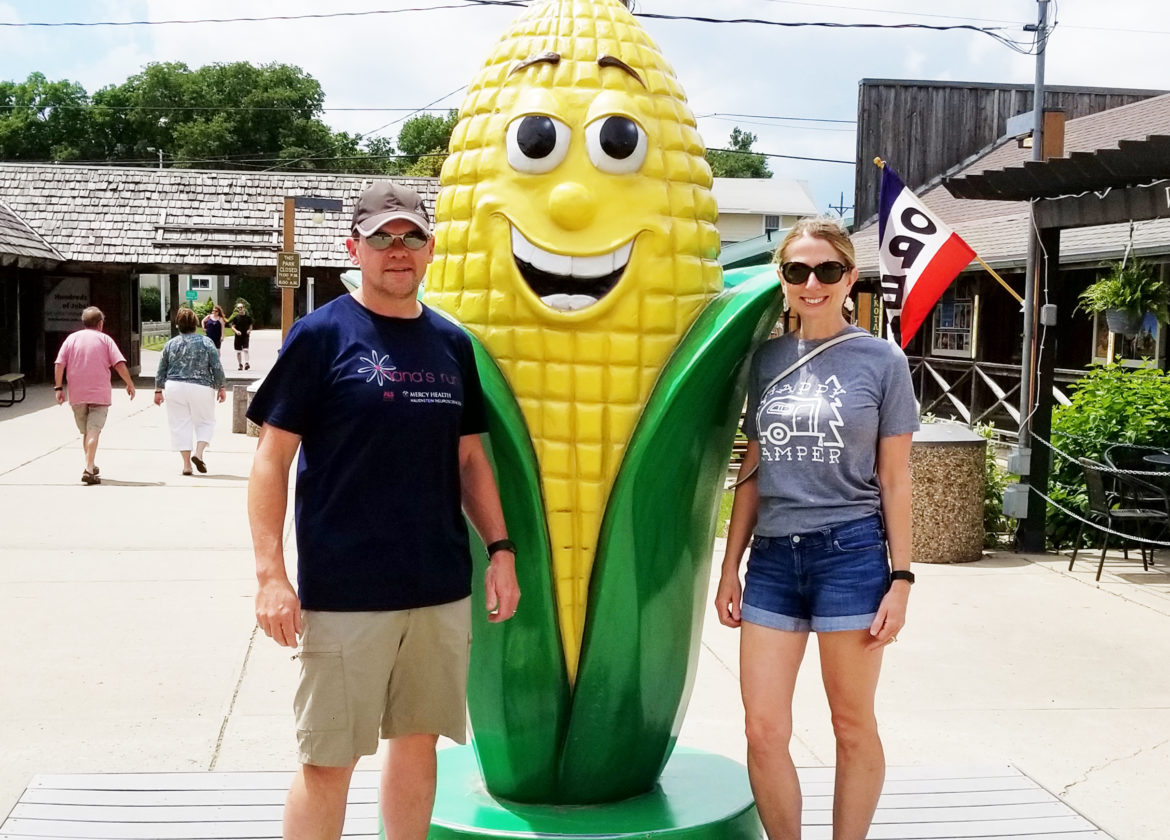 Standing next to a giant ear of corn